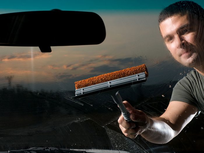 Man cleaning car windshield with club soda
