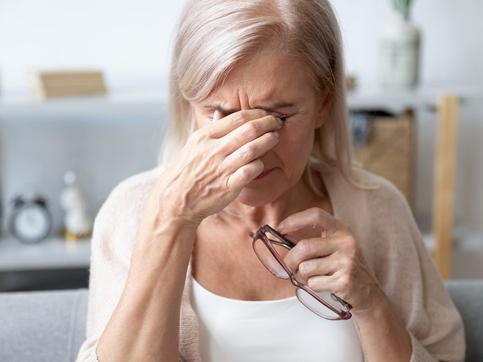 Elderly woman crying wipes tears with hands feels unhappy, bad news. Middle-aged woman taking off glasses closed eyes rubbing eyelid suffers from eye strain deterioration eyesight with age concept