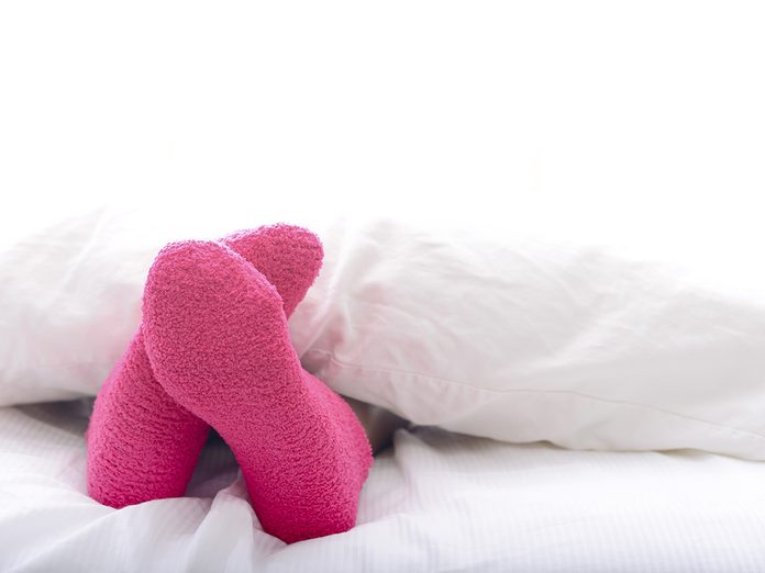 Woman relaxing in bed with pink socks