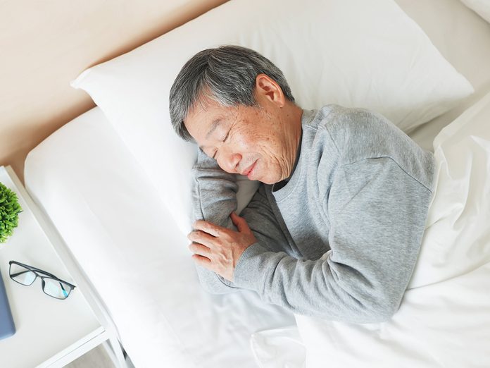 top view of asian senior man lying on bed sleep well with smile in bedroom at home