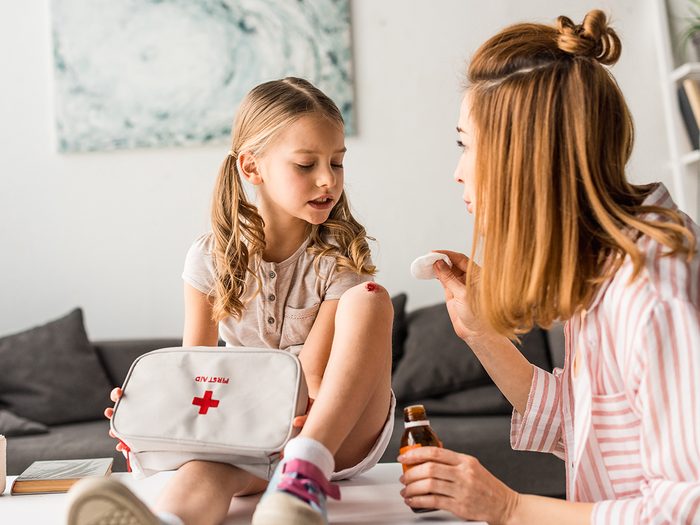 What is in a first aid kit - mother treating injured daughter with antiseptic at home