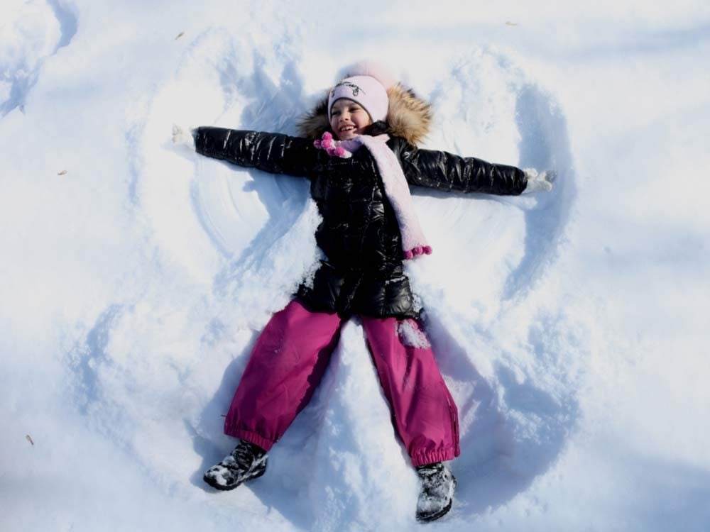 Young girl making snow angel