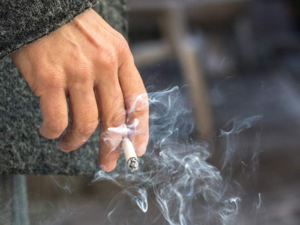 Hand holding lit cigarette