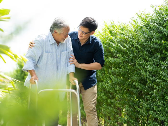 Caring for aging parents - assisting senior using walker