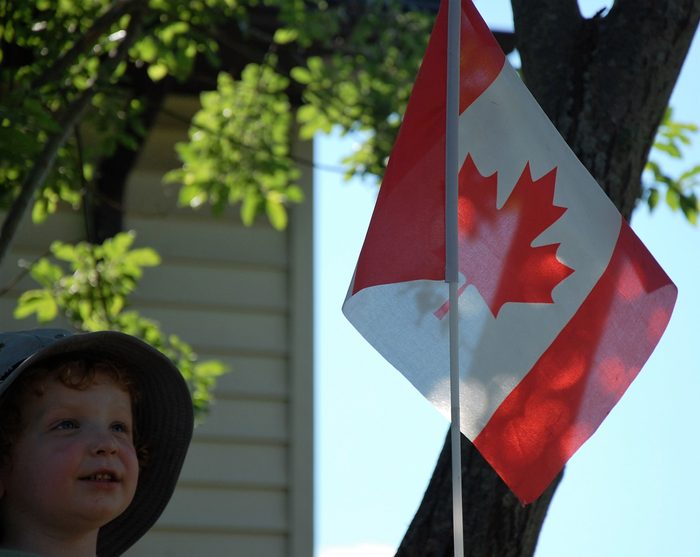 Boy next to Canadian flag at the cottage