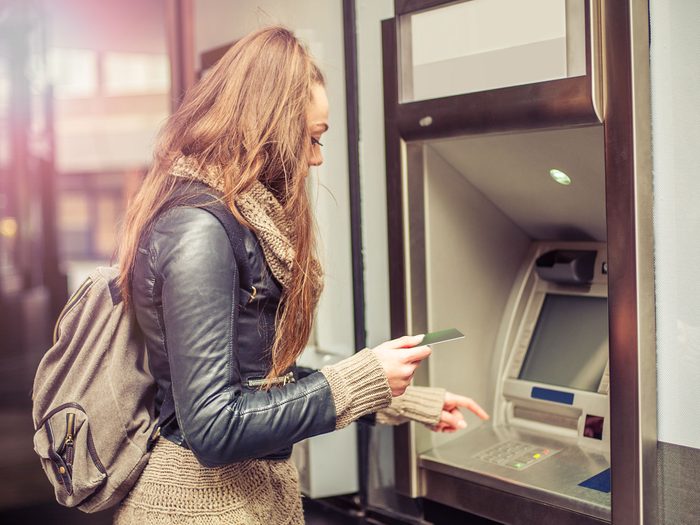 Post-secondary student withdrawing her savings from an ATM