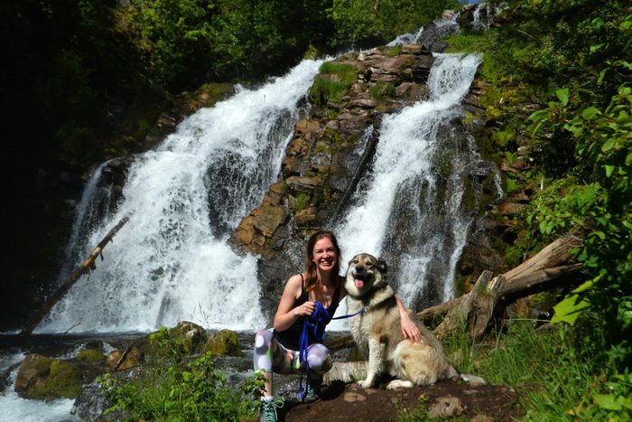 Woman and dog posing near waterfall