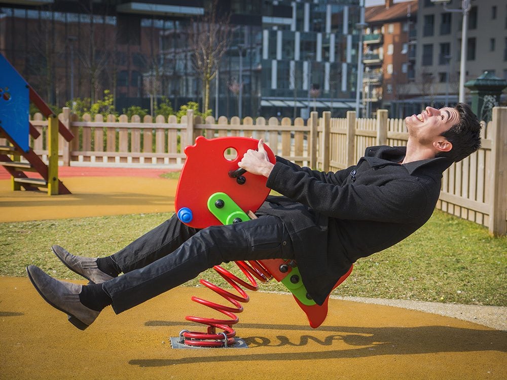 Adult man acting like a child at playground