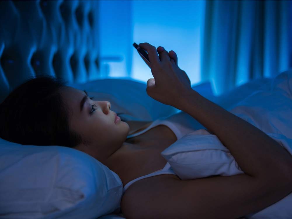 Woman with smartphone in bed before sleep