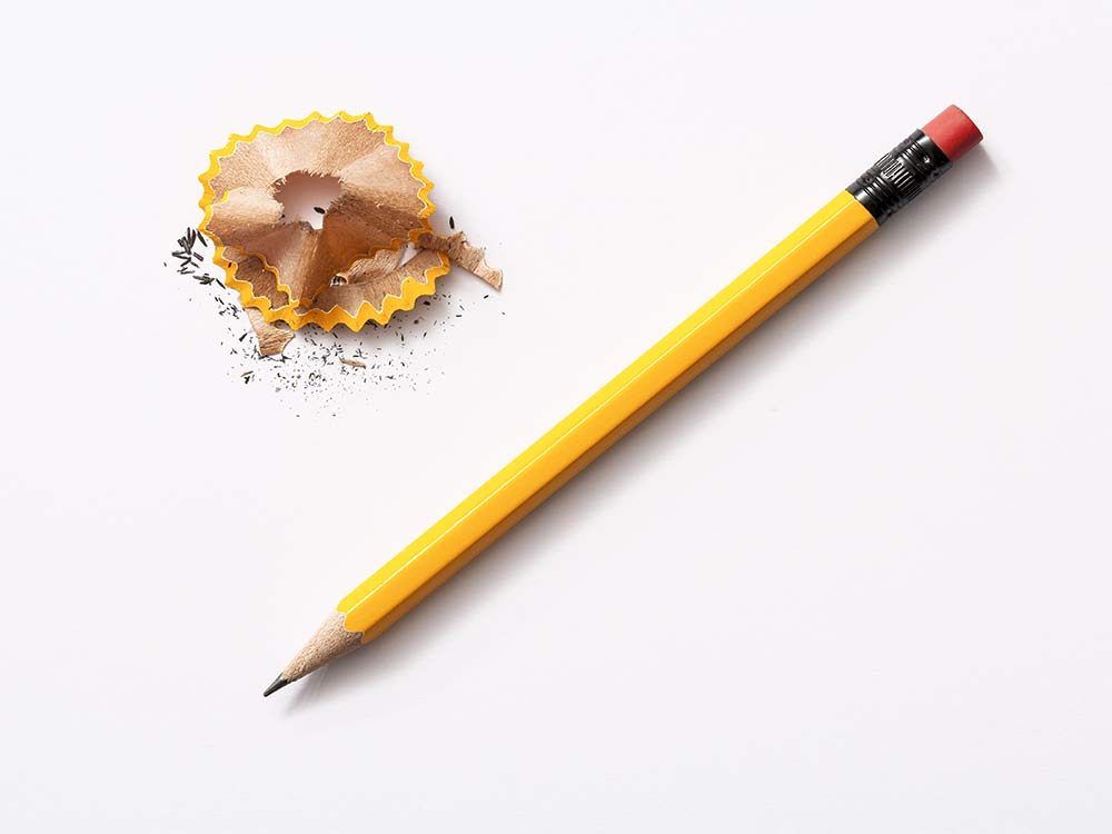 Yellow pencil with pencil shavings on white background