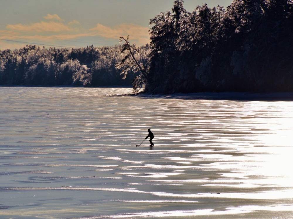 Little boy playing hockey himself on frozen river in Miramichi, New Brunswick
