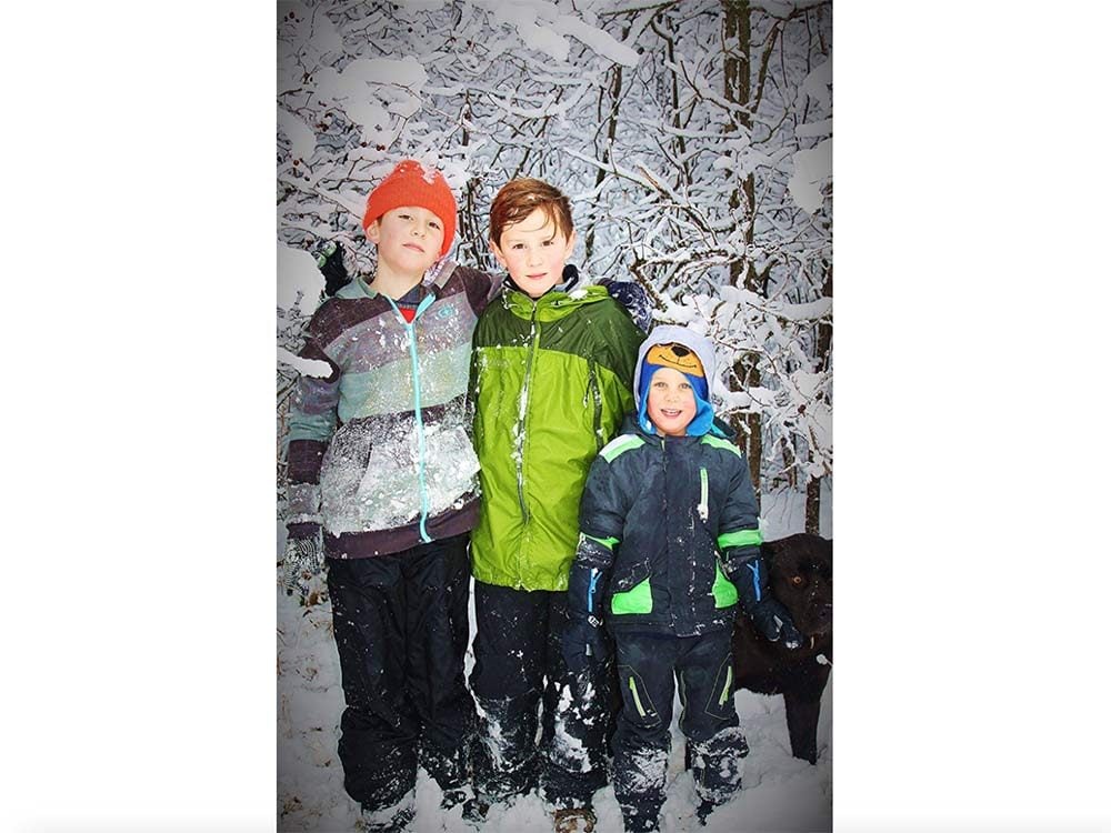 Three young boys posing for photo next to River Bank in Laurier, Manitoba
