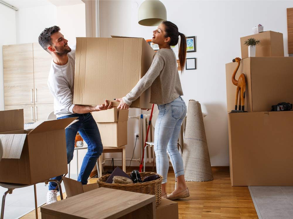 Couple carrying heavy cardboard box on moving day