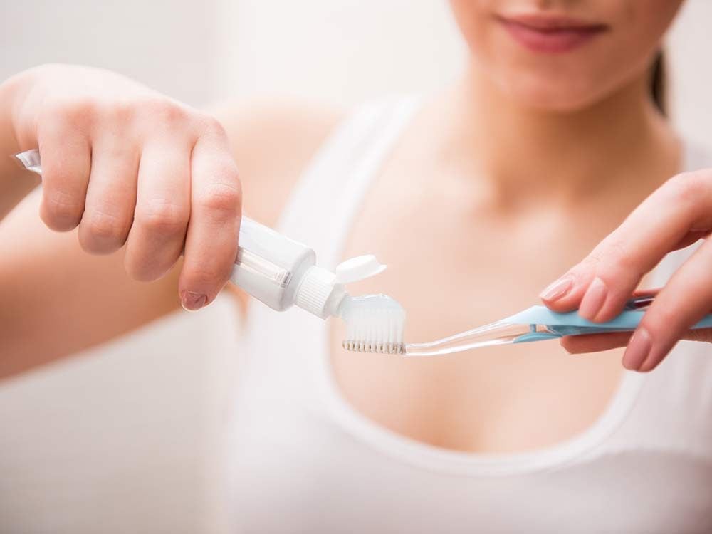 Woman applying toothpaste to toothbrush