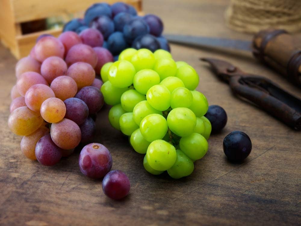 Purple and green grapes on wooden table