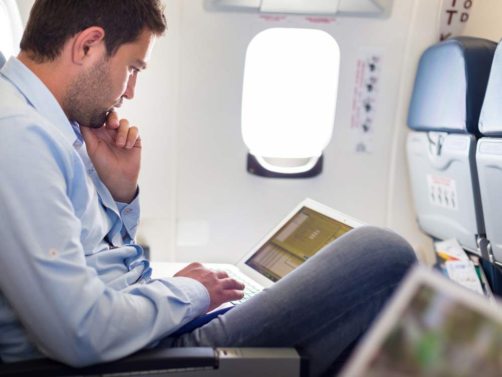 Man using laptop on plane