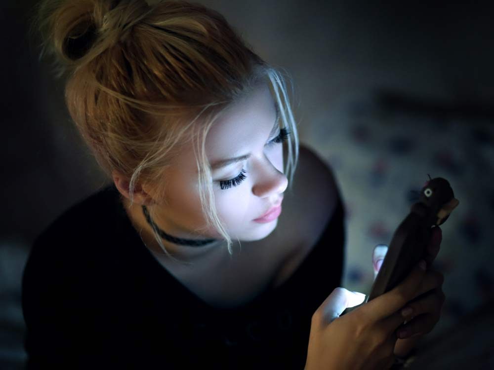 Woman using smartphone in bed at night