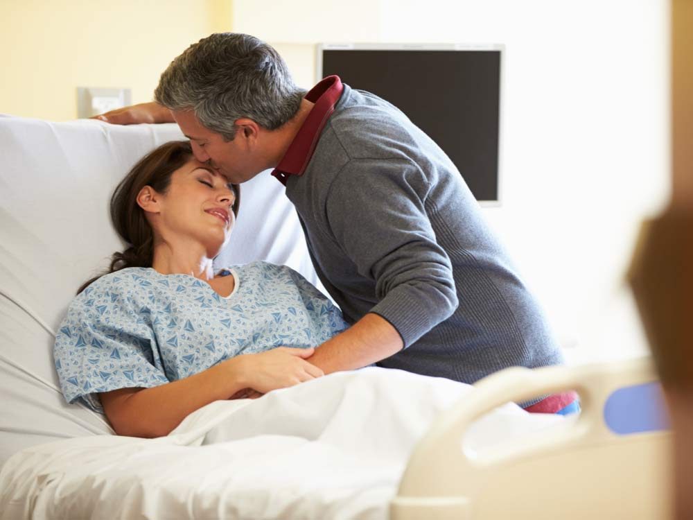 Husband kissing wife on hospital bed