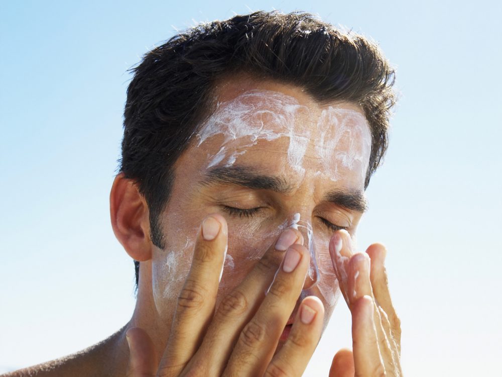 Man applying sunscreen on beach