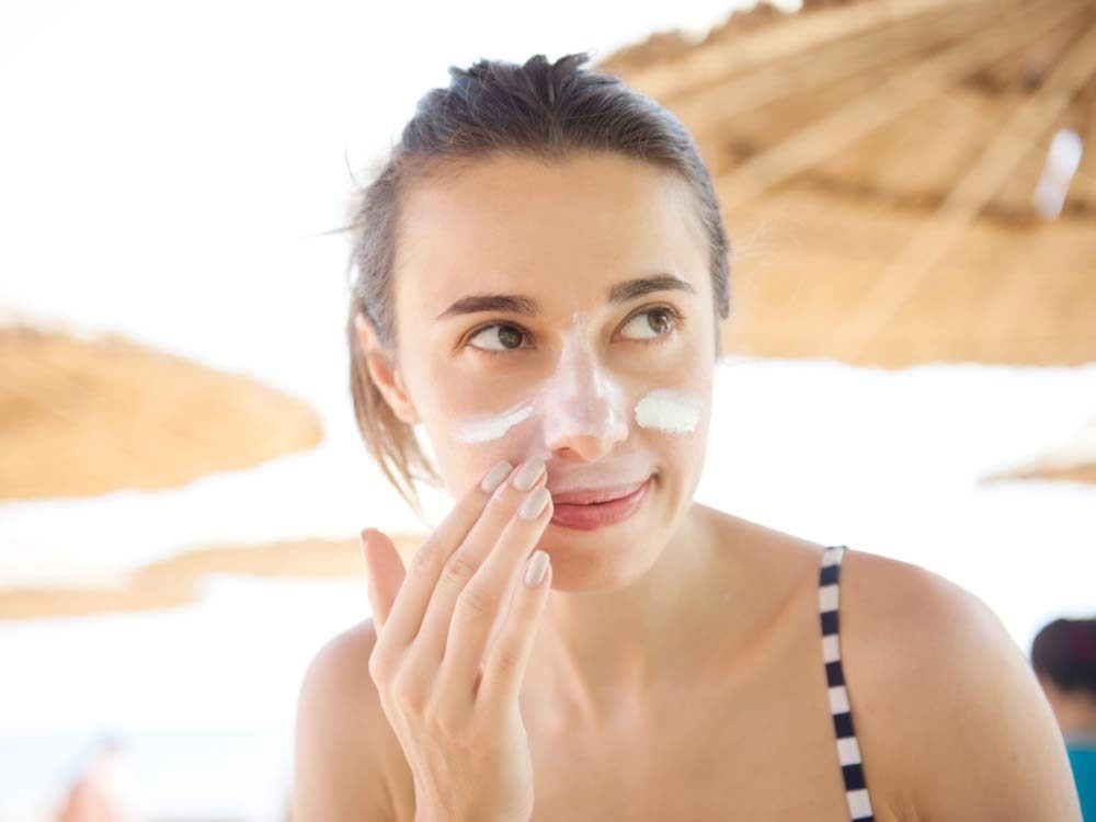 Woman applying sunscreen to face