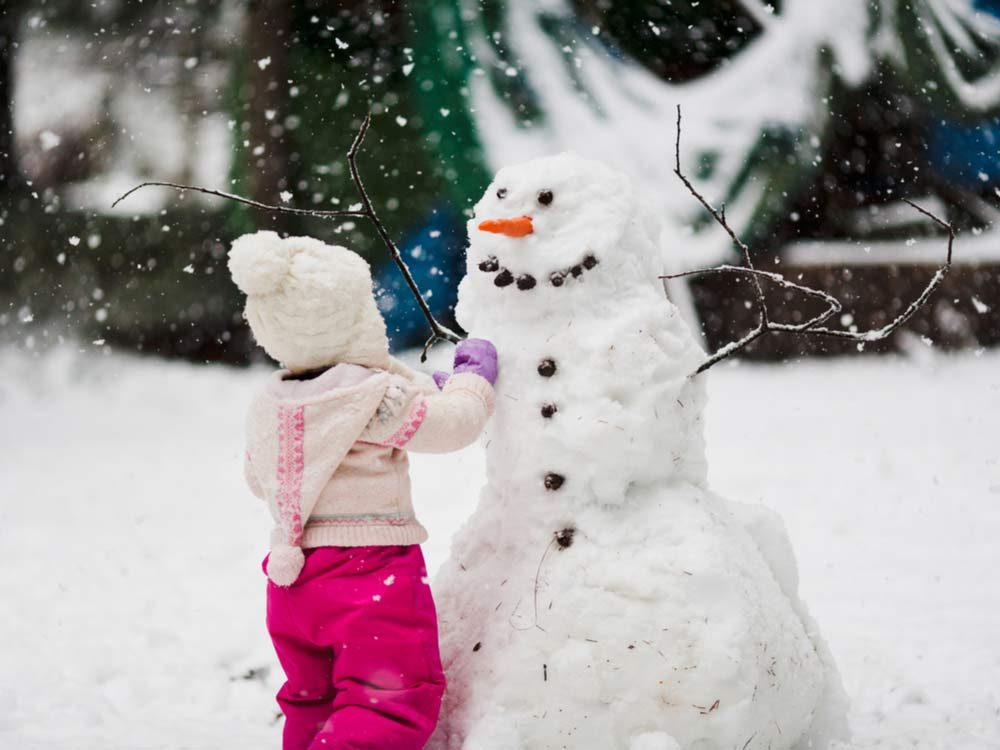 Young girl building snowman