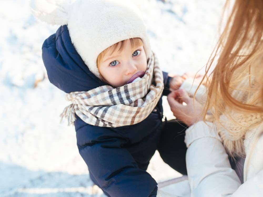 Mother bundling up her young daughter for winter