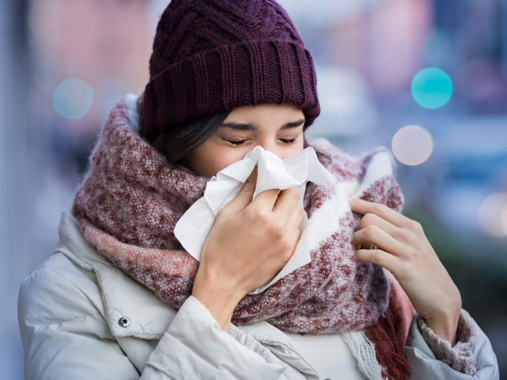 Woman blowing her nose in winter