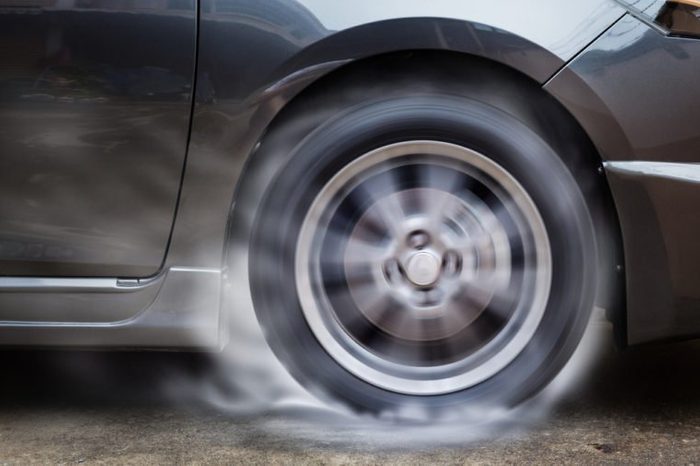 Car racing spinning wheel burns rubber on floor.