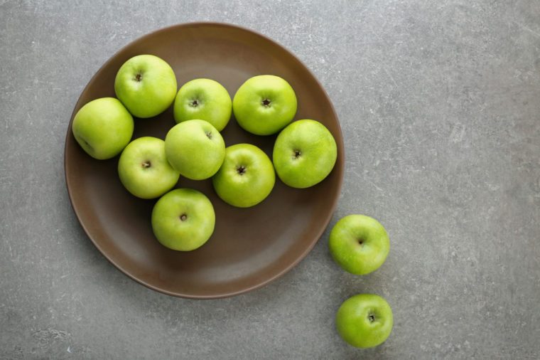 Green apples on wooden plate