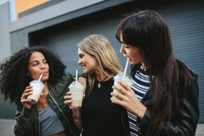 Female friends drinking smoothies outside