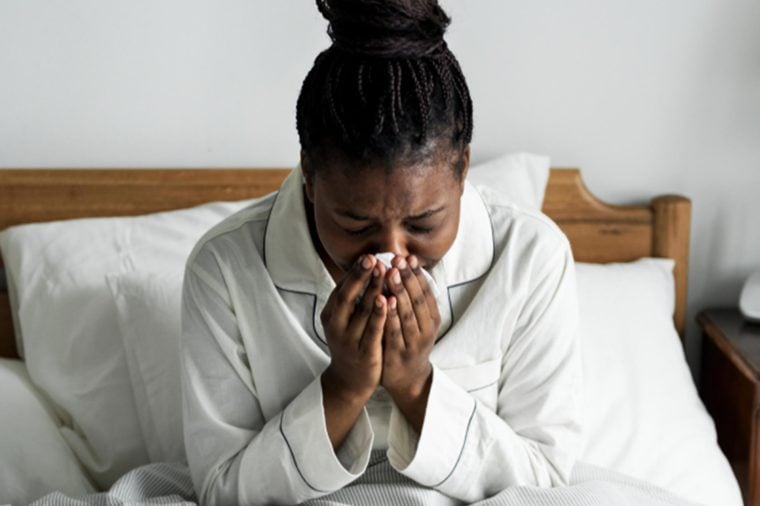 Black woman with allergies sick in bed