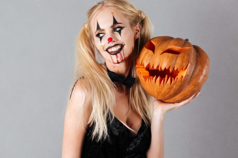 Woman wearing a Halloween costume and carrying a pumpkin