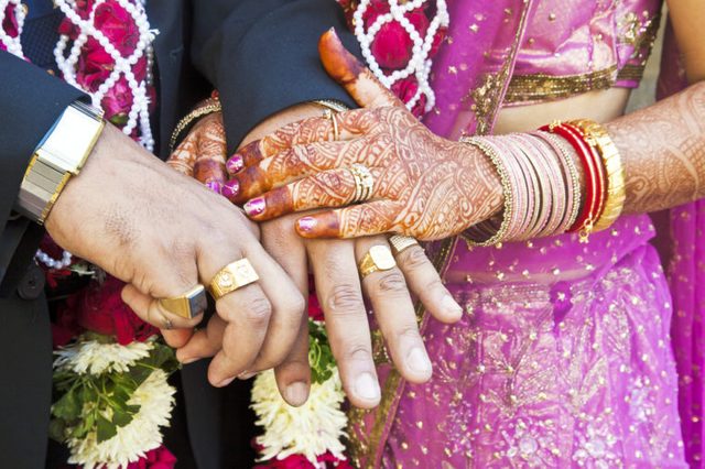 Horizontal color capture taken at a hindu wedding in Surat India. Photo session after the ceremony of the happy hand holding couple displaying their rings of matrimony and the bride lays her claim