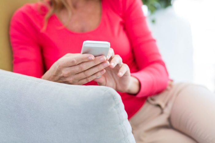 Midsection of woman using mobile phone on couch at home