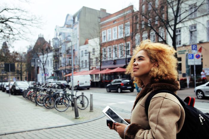 young pretty african american girl with curly hair making photo on a tablet, lifestyle people concept, tourist in european german city