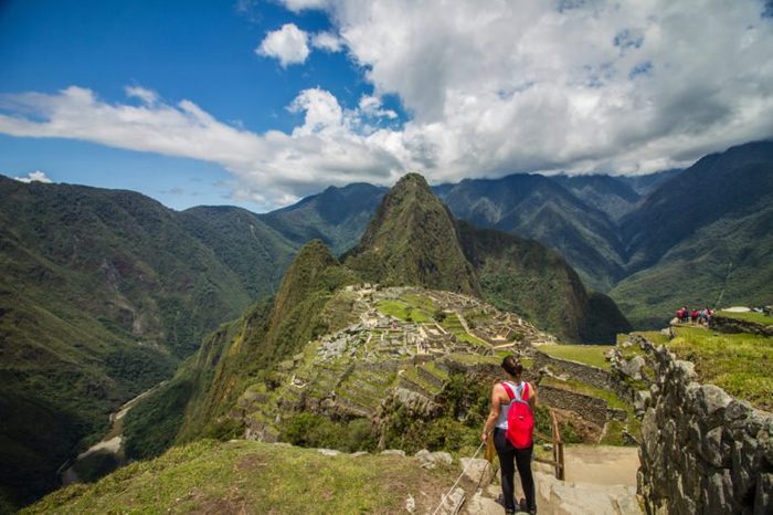 Young Adventure Girl traveler observinng in front of the Majestic Machu Picchu ruins- Peru.