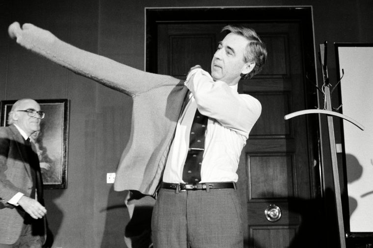 Fred Rogers putting on his trademark sweater