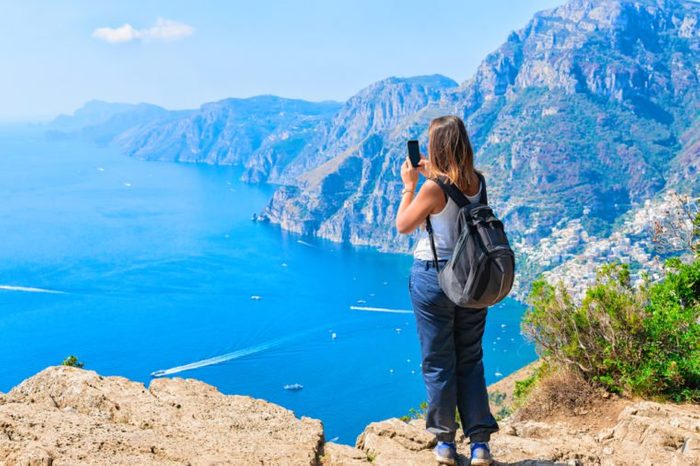 Woman taking photos of beautiful scenery at Path of Gods on Tyrrhenian sea, Amalfi coast, Italy