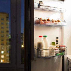 Open fridge door with eggs and dairy