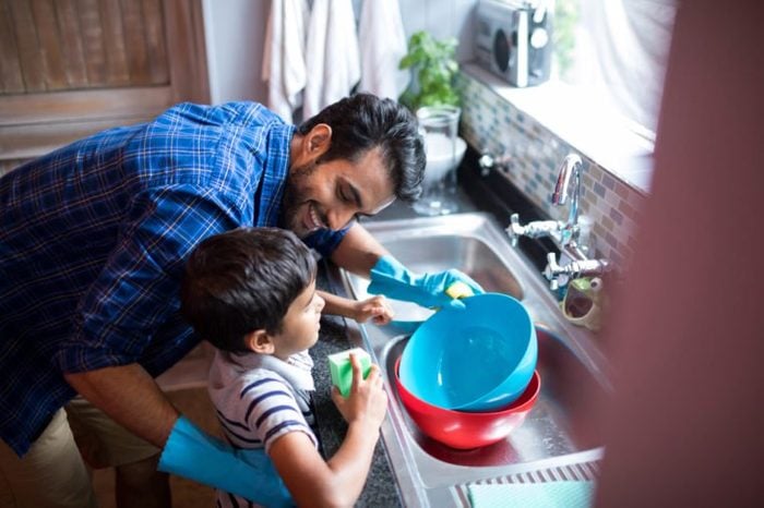 High angle view of father and son cleaning utensils at home