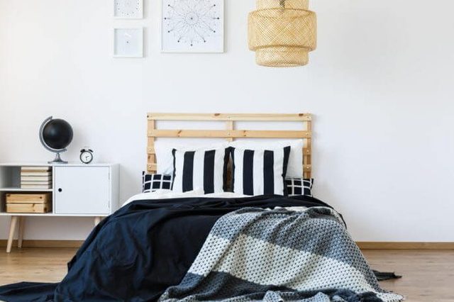 Comfortable bed with wooden headboard and black and white bedding
