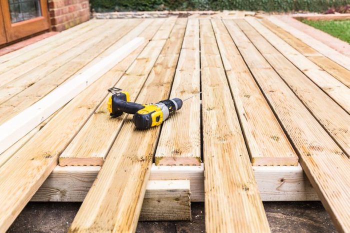 A new wooden, timber deck being constructed. it is partially completed. a drill can be seen on the decking.