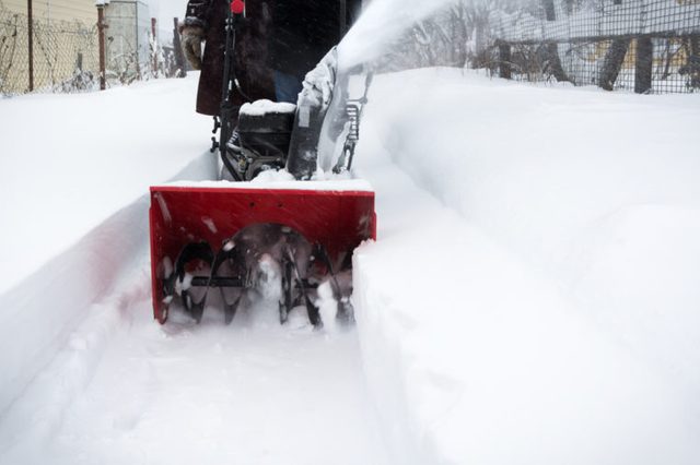 Man clears snow with snow blower after snowfall