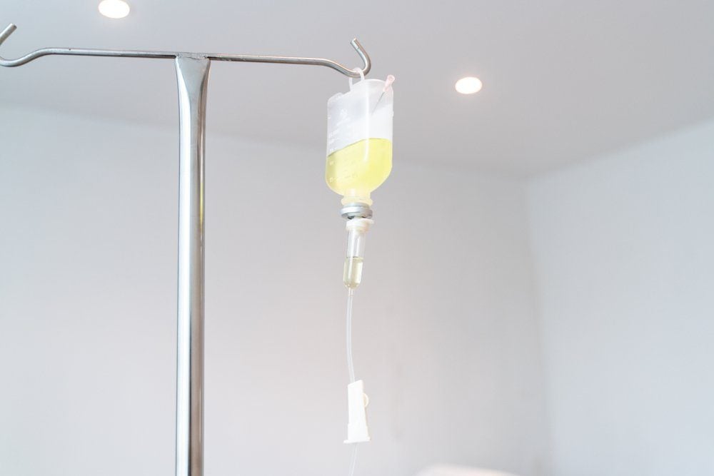 Drop of Saline Solution,IV drip chamber, IV tubing hanging on a metal pole in the room