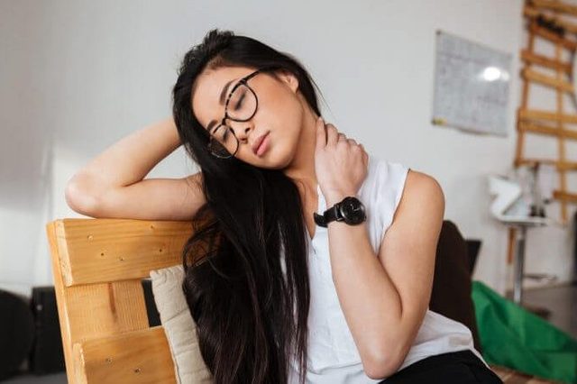 Tired exhausted asian young woman in glasses sitting and relaxing