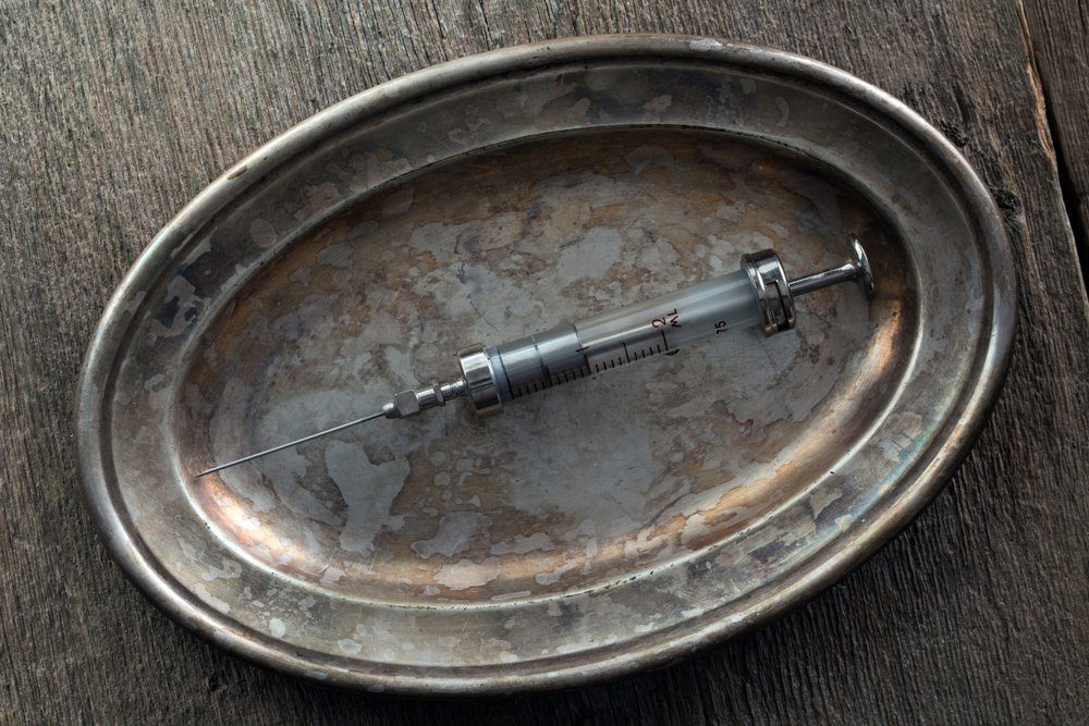Glass syringe on an old silver tray