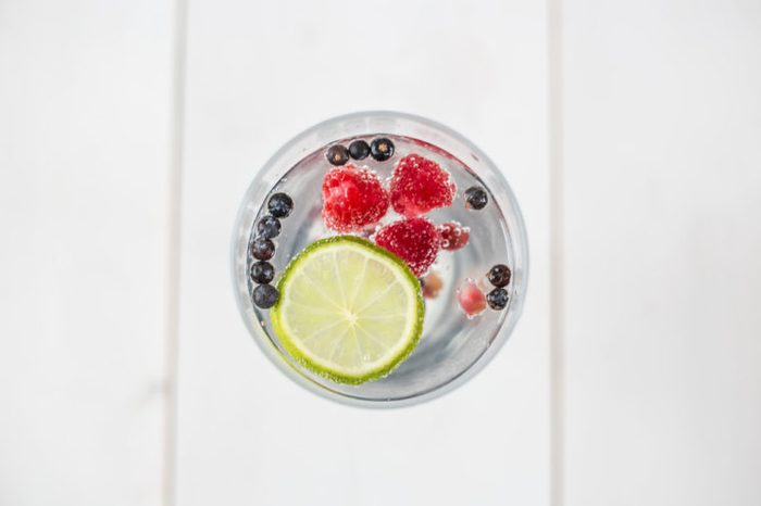Top view of a refreshing Gin & Tonic with raspberries, lime, blueberries, pomegranate and dried spiced berries