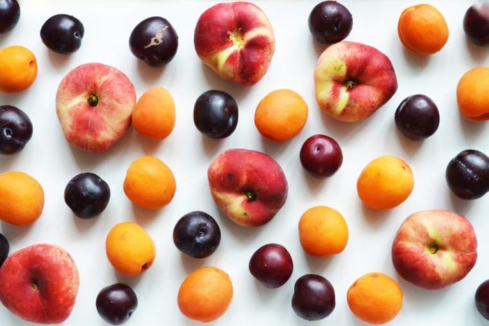 Delicious ripe summer fruits on a white background. Composition of peaches, plums, apricots. View from above.