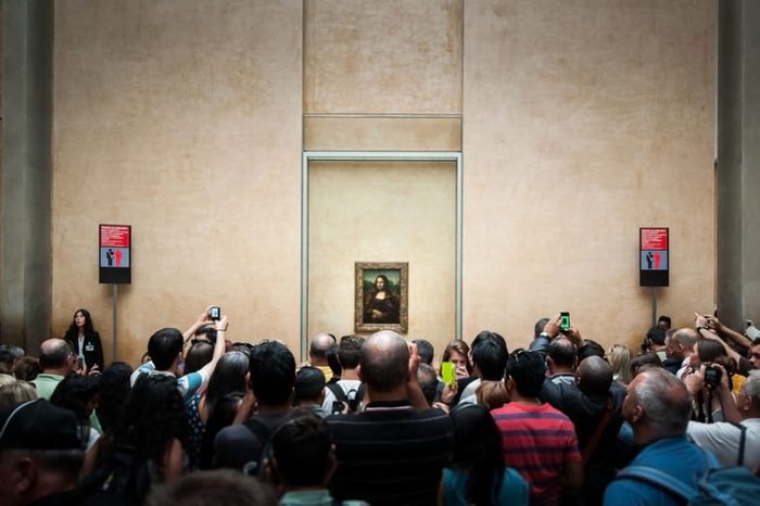 PARIS, FRANCE - JUNE 18 , 2014 : A many of visitors take photos of "Mona Lisa" , by Leonardo DaVinci's at the Louvre Museum, june 18, 2014 in Paris, France.