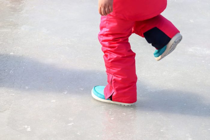The legs of a girl walking on ice.